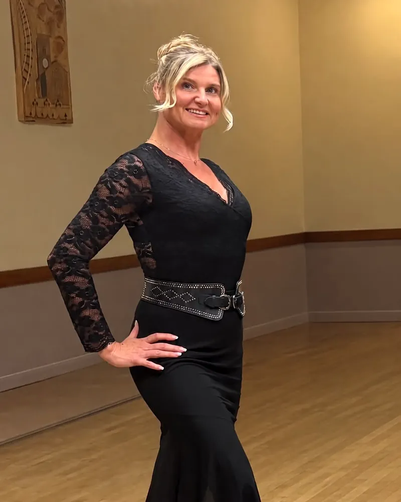 Justyna Wells, dance teacher at WellSway Dance Studio, in a black lace dress striking a dance pose in the hall